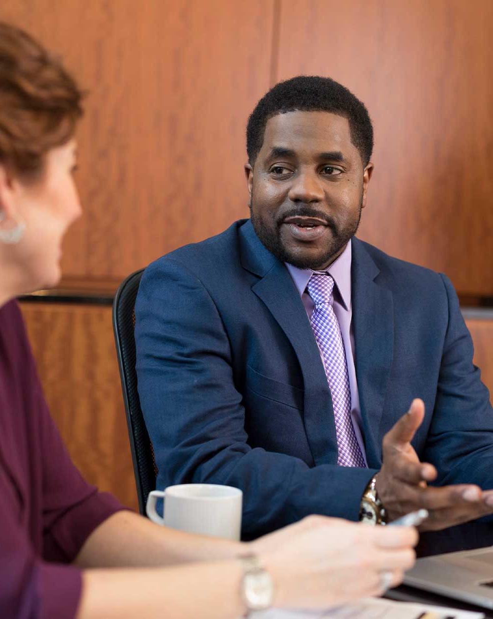 Black man in a suit talking with a colleague 